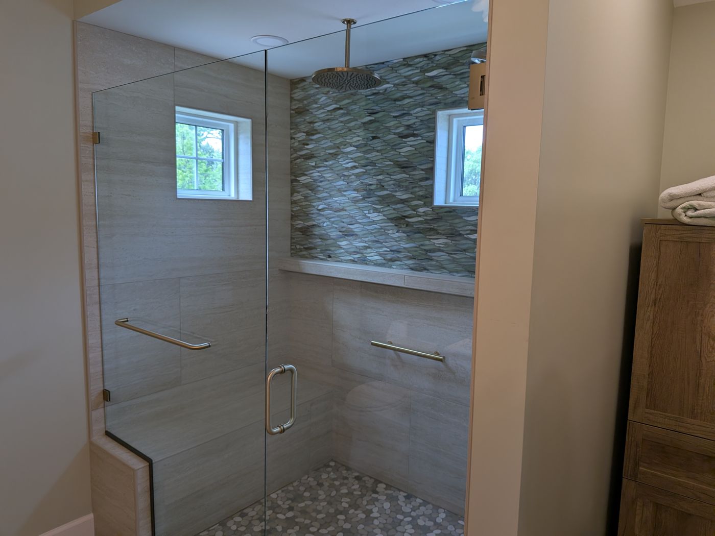 Frameless shower with brushed gold hardware and mosaic accent wall
