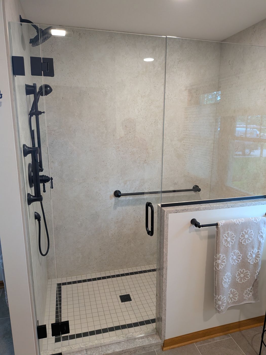 Frameless shower door and panel on a knee wall with matte black hardware